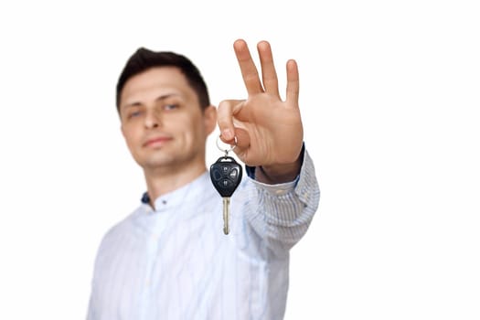 caucasian man holding car keys on white background. Car dealerships. focus on key
