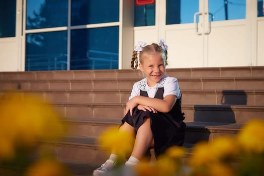 Little girl of elementary school student in modern school uniform outdoors with bouquet of flowers. Female child schoolgirl going to school. Back to school in september 1 in Russia