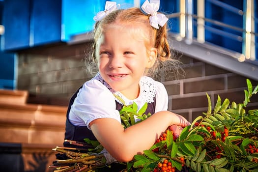 Little girl of elementary school student in modern school uniform outdoors with bouquet of flowers. Female child schoolgirl going to school. Back to school in september 1 in Russia