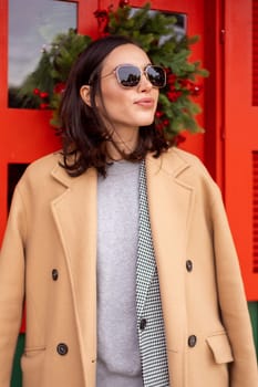 Happy caucasian girl walking Christmas holiday winter day in European city. Brunette woman wears stylish jacket, coat and sunglasses. Positive emotions lifestyle concept