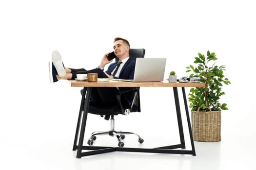 Successful happy businessman working with laptop and having phone conversation with client