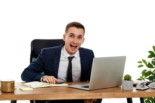 Upset angry businessman sitting on chair at desk after talking on the phone, using laptop