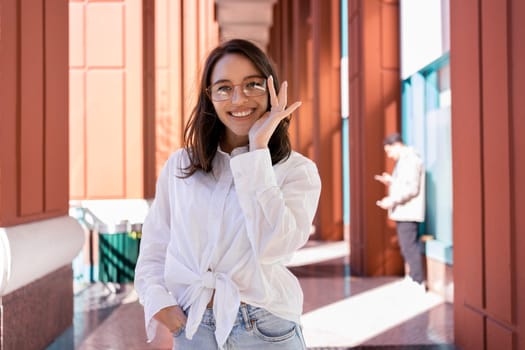 Successful smiling business woman wearing eyeglasses correct glasses by hand. Modern businesswoman smile standing outdoor dressed white shirt. Business woman happy positive emotions