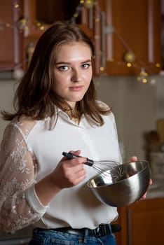 girl prepares a cream for a festive Christmas cake in a kitchen decorated for Christmas