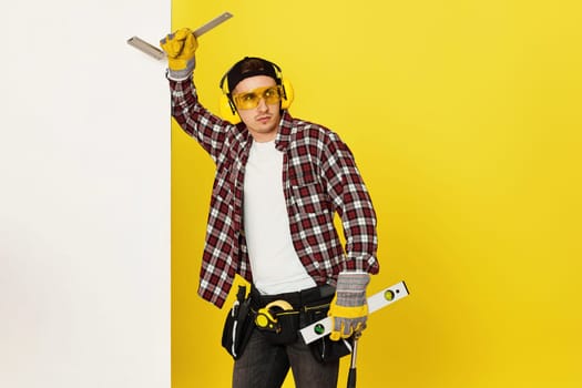 Worker man or builder in construction helmet near white banner on yellow background. building carpentry profession