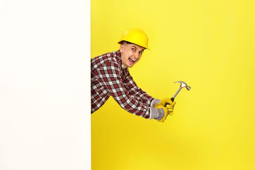 professional builder in work clothes in helmet holding hammer. copy space for text