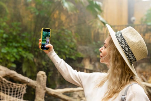 Woman taking selfie on phone in botanical garden .