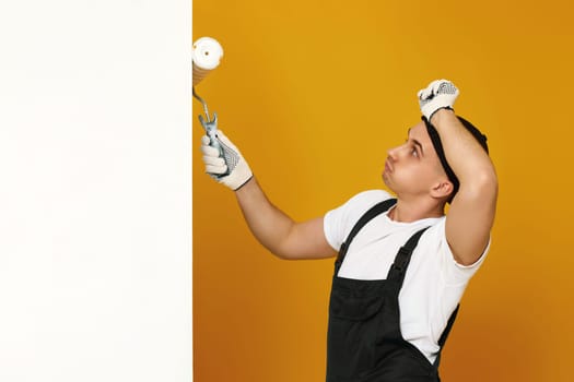 tired man in working clothes work with paint roller, wall painting, web banner and copy space