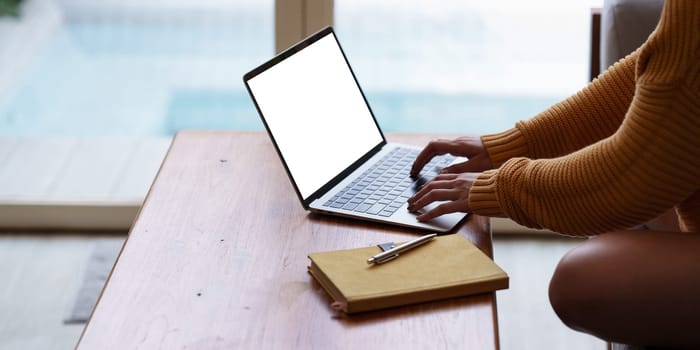 Online education, e-learning. Asian woman in stylish casual clothes, studying using a laptop, listening to online lecture, taking notes, online study at home.