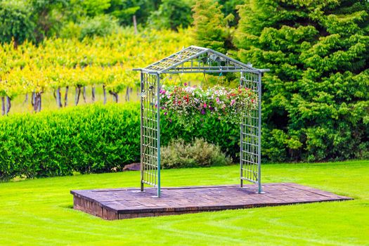 Archway decorated with colorful flowers, in front of vineyard