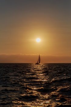 Sailboat far at horizon, in front of  beautiful sunset.