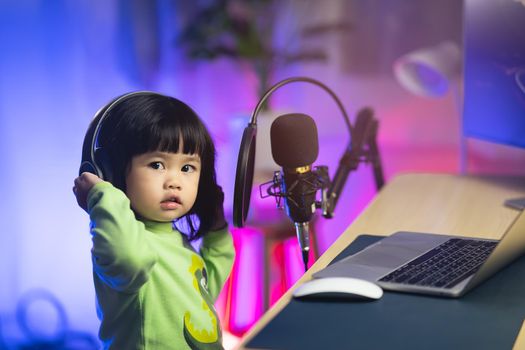 cute baby girl singing with headphone recording new song with microphone in the home recording studio