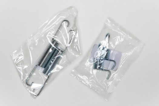 A set of metal springs in the package, parts for car repair. A set of spare parts for servicing vehicle calipers. Details on white background, copy space available.