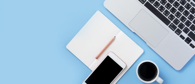 Girl write on open white book or accounting on a minimal clean light blue desk with laptop and accessories, copy space, flat lay, top view, mock up