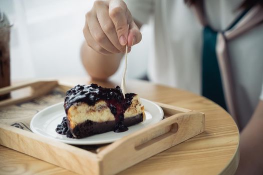 Women eating blueberry cheesecake on the wood table in the cafe