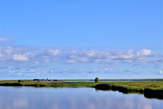 landscape at the coast of the north sea against a blue cloudy sky