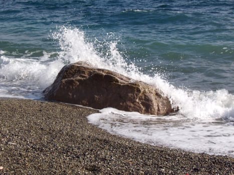 Waves and splashes of sea surf and stone on the seashore. Stones and shells on the beach.