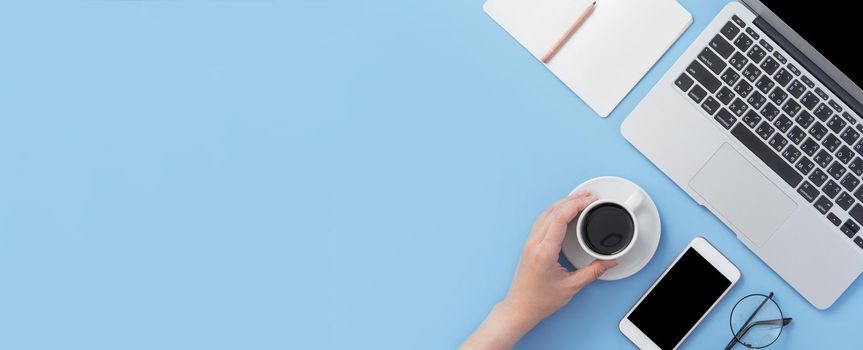 Business concept. Clean bright light blue office table desk, minimal style with laptop coffee and smart phone, copy space, top view, flat lay, mockup