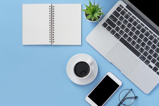 Business concept. Clean bright light blue office table desk, minimal style with laptop coffee and smart phone, copy space, top view, flat lay, mockup