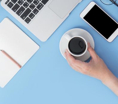 Business concept. Clean bright light blue office table desk, minimal style with laptop coffee and smart phone, copy space, top view, flat lay, mockup