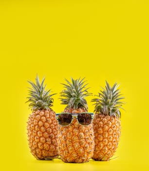 Creative pineapples with sunglasses isolated on yellow background, summer vacation beach idea design pattern, copy space, close up, blank for text