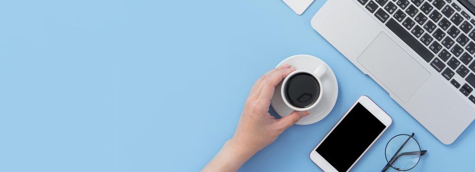 Business concept. Clean bright light blue office table desk, minimal style with laptop coffee and smart phone, copy space, top view, flat lay, mockup