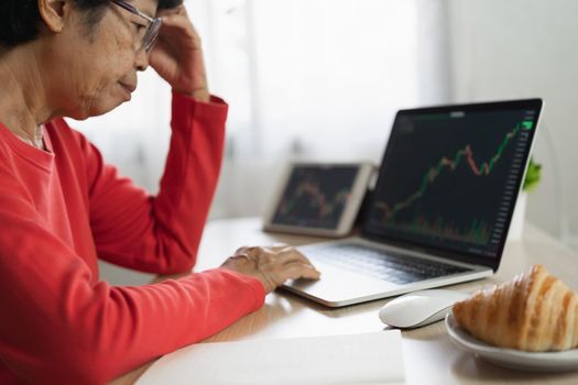 Senior woman depression and serious about checking Bitcoin price chart on digital exchange on laptop