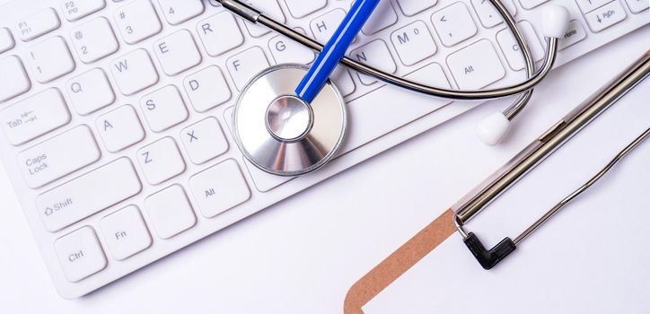 Stethoscope on computer keyboard on white background. Physician write medical case long term care treatment concept, top view, flat lay, copy space