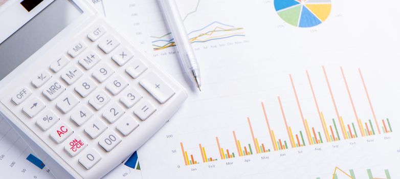 White calculator and report with chart and graph, concept of annual financial profit overview, banking and investment, close up, copy space, macro