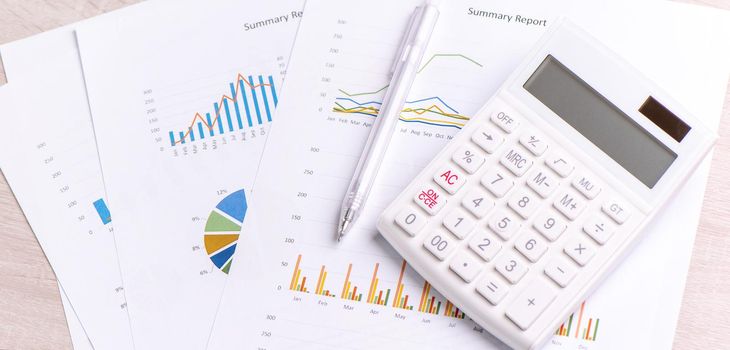 White calculator and report with chart and graph, concept of annual financial profit overview, banking and investment, close up, copy space, macro