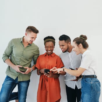 Help me choose a picture. a diverse group of businesspeople standing against a gray background together and using technology in the office