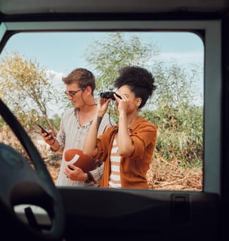 Window, car and diversity couple on road trip journey to explore Australia safari, countryside or outdoor nature. Binocular, transportation adventure and man streaming football game on mobile phone.