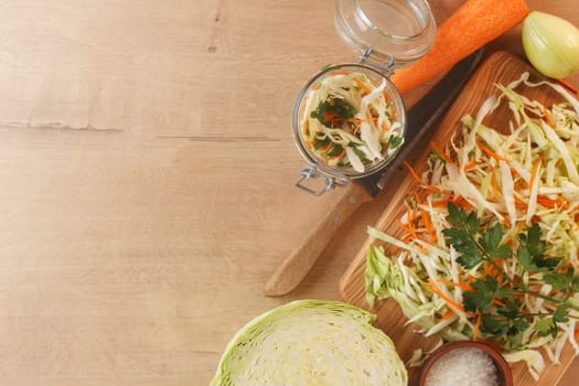 Cabbage lies on a wooden board with carrots, onions and herbs. Preparing to cook cabbage dishes.Copy space