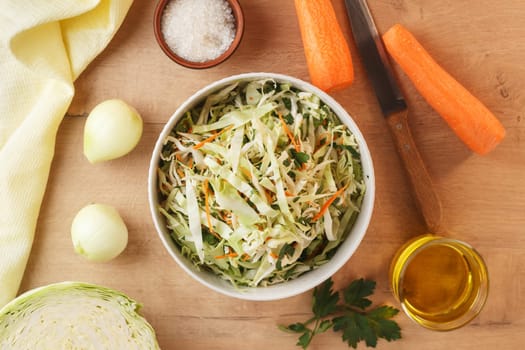 healthy vegan bowl of vegetable salad for lunch. Cabbage, carrots, parsley, onion, olive oil. View from above