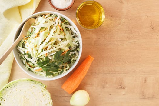 healthy vegan bowl of vegetable salad for lunch. Cabbage, carrots, parsley, onion, olive oil. Copy space