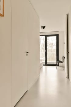 a long hallway with white walls and black trim on the doors, leading you to an open space where there is no one person