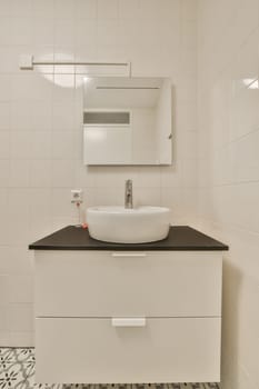 a white bathroom with black and white tiles on the floor, sink and mirror in the corner wall behind it