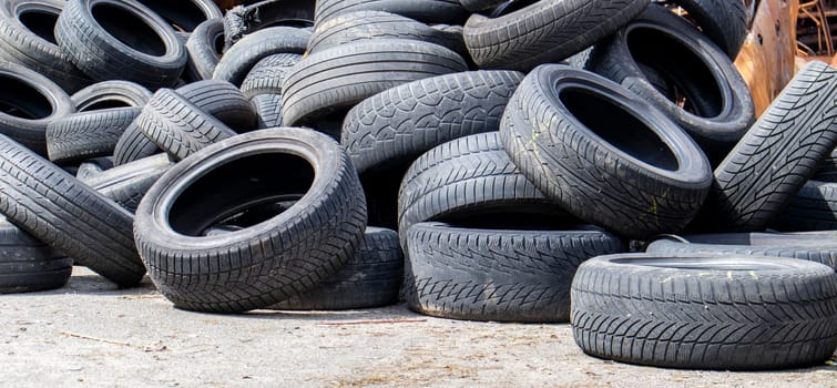 Industrial dump for the processing of used tires and rubber tires. Pile of old tires and wheels for rubber recycling. Tire dump. Recycling of used tires. Produced reclaimed tire rubber