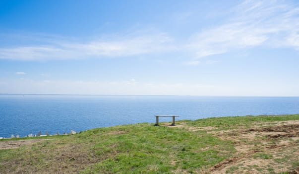 Wooden bench on the shore of the blue sea, lake on a summer sunny day