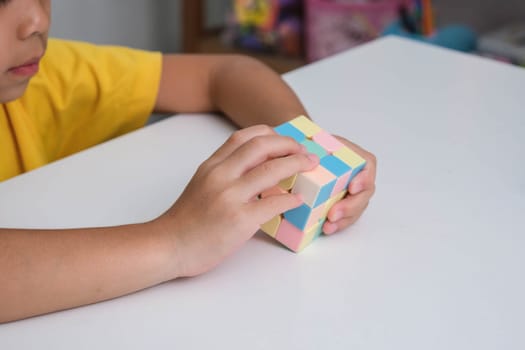 Asian little cute girl holding Rubik's cube in her hands and playing with it. Rubik's cube is a game that increases intelligence for children. Educational toys for children