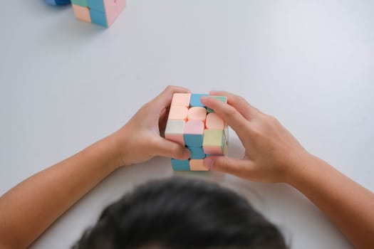Asian little cute girl holding Rubik's cube in her hands and playing with it. Rubik's cube is a game that increases intelligence for children. Educational toys for children