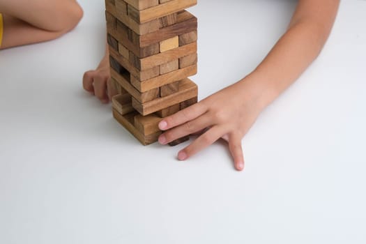 Cute Asian siblings having fun playing Jenga together. Two children playing Jenga board game on table in room at home. Wooden puzzles are games that increase intelligence for children. Educational toys for children.