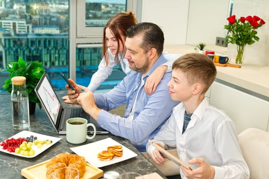 Young family with school kids have fun at breakfast time. Happy family eating healthy breakfast. Quality time with Family in kitchen eating together. Family Using Digital Devices At Breakfast