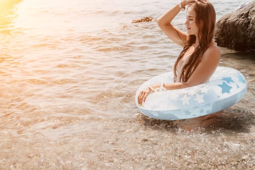 Woman summer sea. Happy woman swimming with inflatable donut on the beach in summer sunny day, surrounded by volcanic mountains. Summer vacation concept