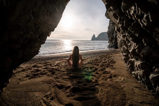 Middle aged well looking woman with black hair doing Pilates with the ring on the yoga mat near the sea on the pebble beach. Female fitness yoga concept. Healthy lifestyle, harmony and meditation.