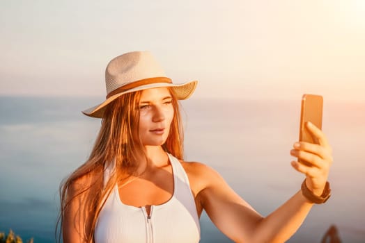 Woman travel sea. Happy tourist in hat enjoy taking picture outdoors for memories. Woman traveler posing on the beach at sea surrounded by volcanic mountains, sharing travel adventure journey