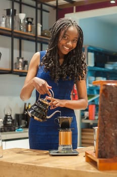 BLACK girl in elegant blue dress demonstrating how to make coffee smiling at camera. High quality photo