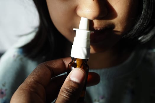 close up of sick child using nasal medicine spray.