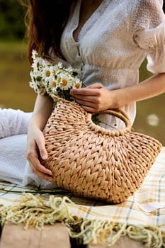 a woman gently touches the daisies lying in a wicker bag. photograph without a face. High quality photo