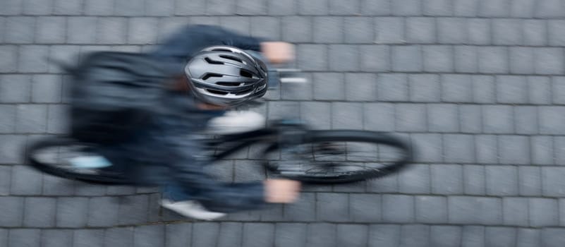Bike, motion blur and overhead with a person cycling on a brick road at speed to commute in the city. Bicycle, travel and fast with a cyclist sitting whileriding on eco friendly wheels for traveling.